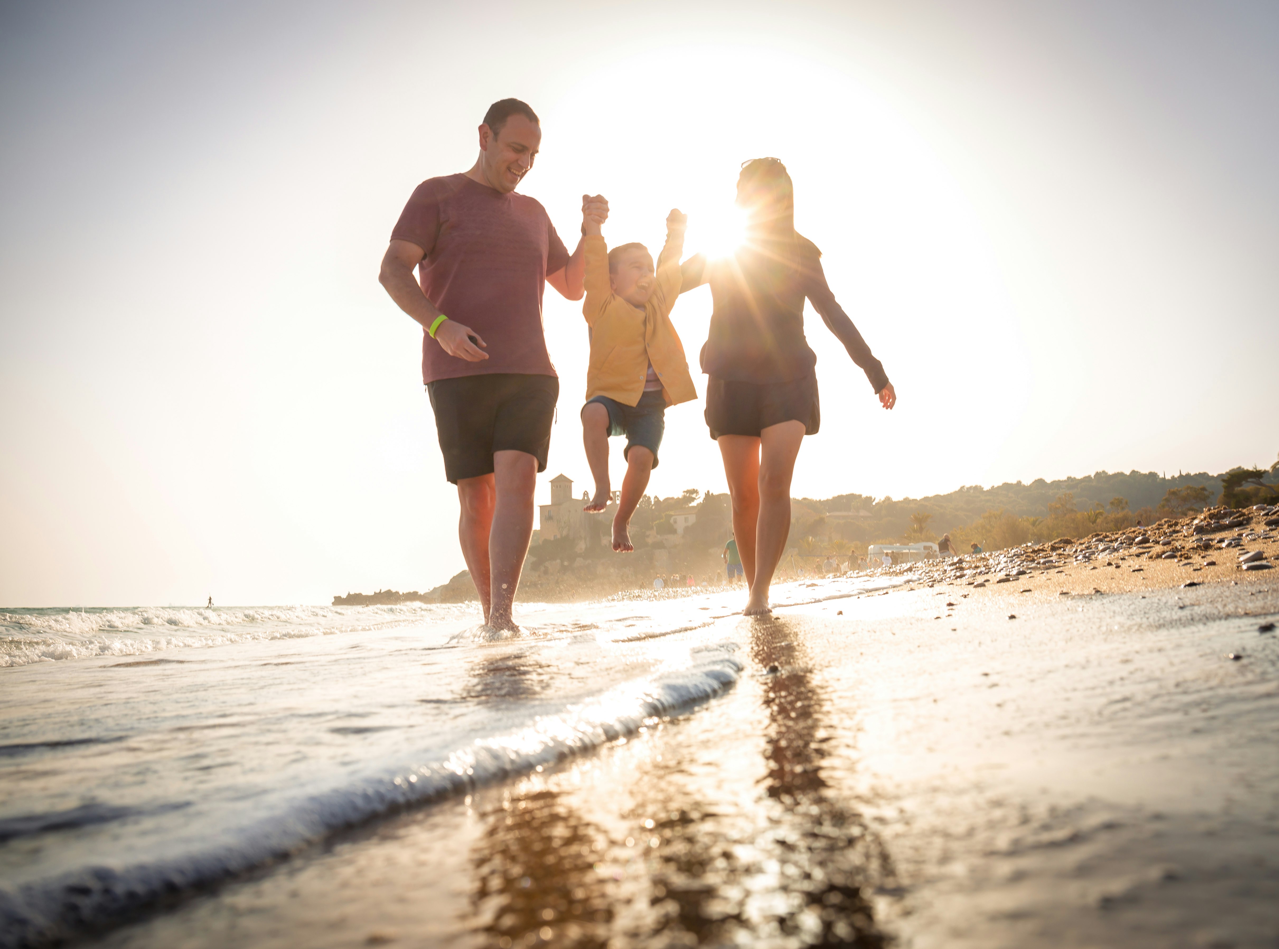 2 men and woman walking on beach during daytime